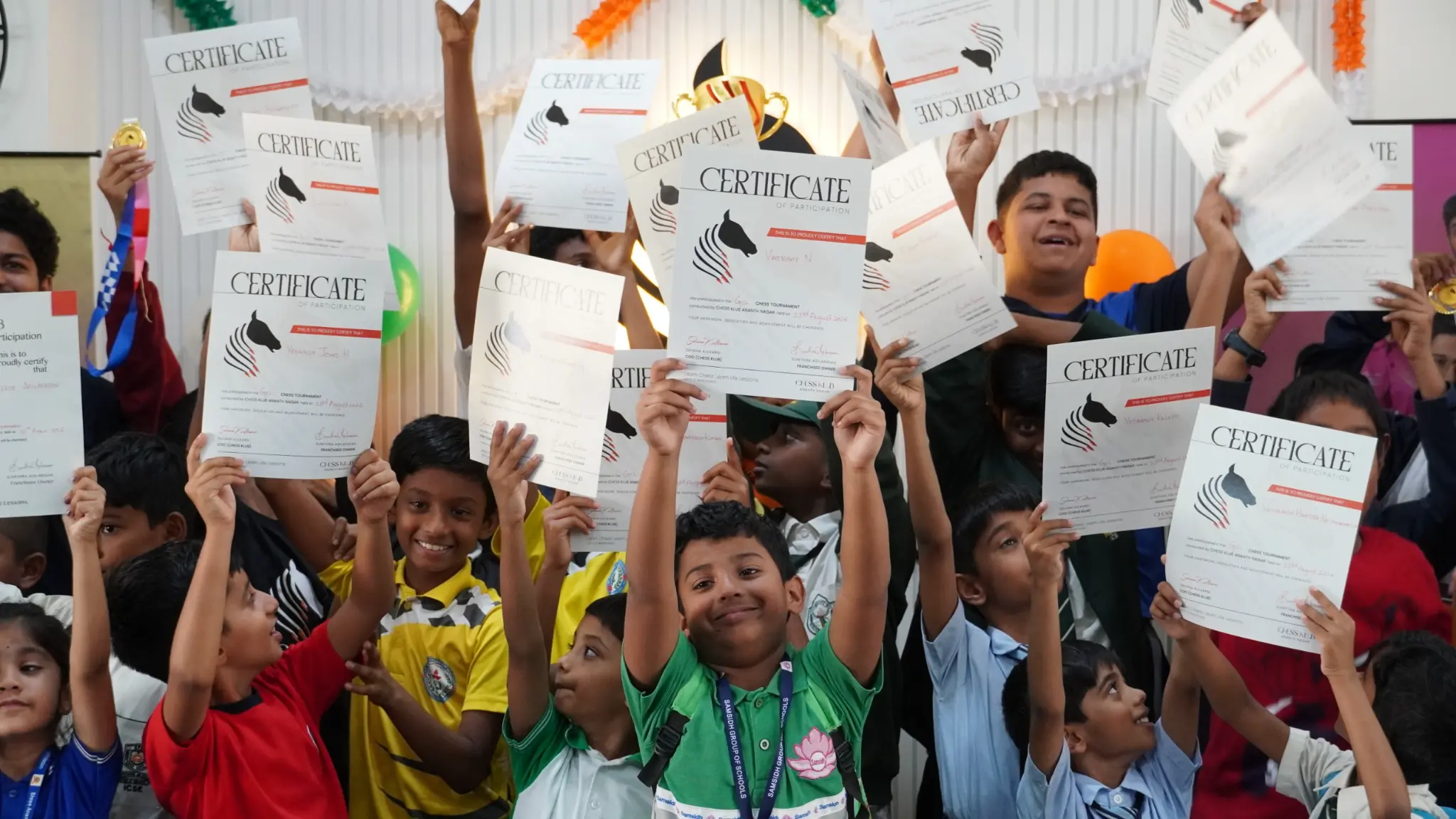 Children at a CHESS KLUB event smiling and celebrating with their certificates